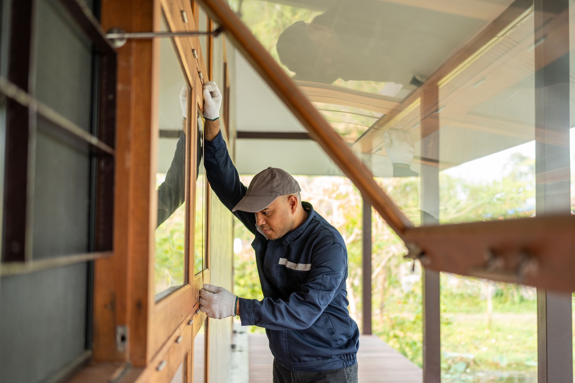 Technician worker in uniform using measuring tape tool to measuring wood window in the home construction site. repair and fix for problem in the house